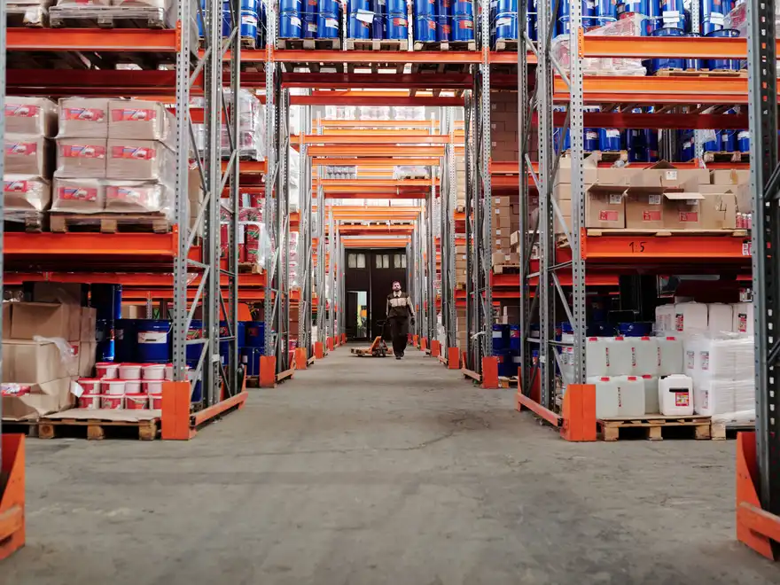 A long warehouse aisle lined with tall pallet racking stacked to the roof with cartons.